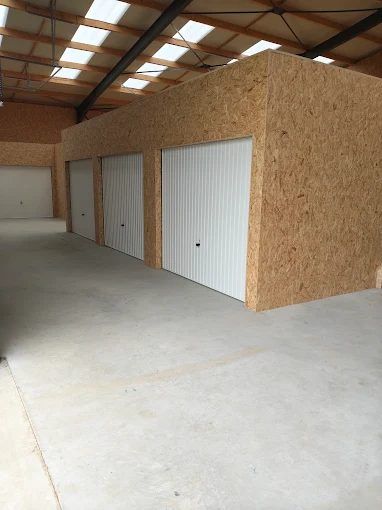 Box en bois sous la charpente métallique éclairée par des puits de lumière