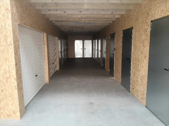 Allée bétonnée bordée de portes de box de chaque côté